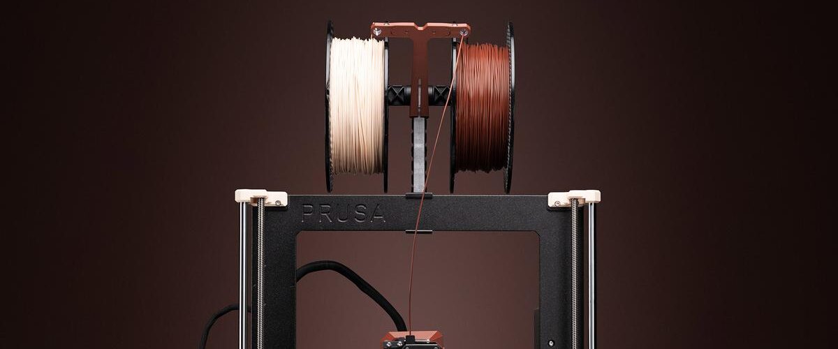 Zwei Spulen Prusament PETG Filament in den charakteristischen Noctua-Farben Beige und Braun, vor einem subtilen Hintergrund.
